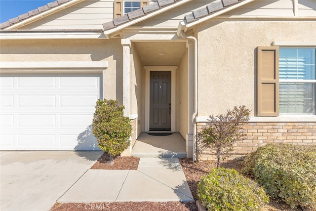 entrance to property with a garage and stucco siding