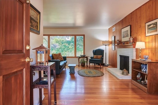 living area featuring a fireplace, wood finished floors, visible vents, and wooden walls