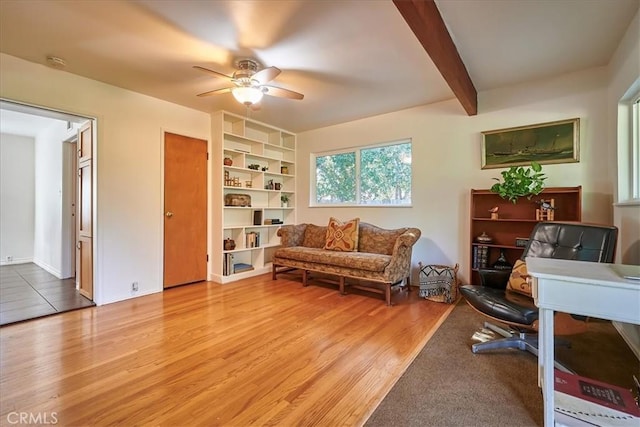 sitting room with ceiling fan, wood finished floors, and beam ceiling