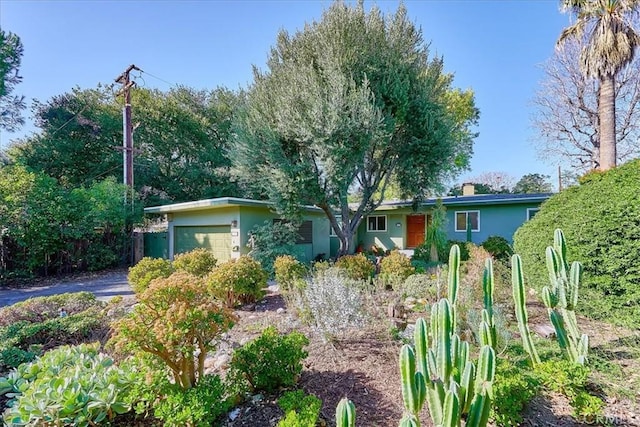 single story home featuring a chimney, an attached garage, and stucco siding