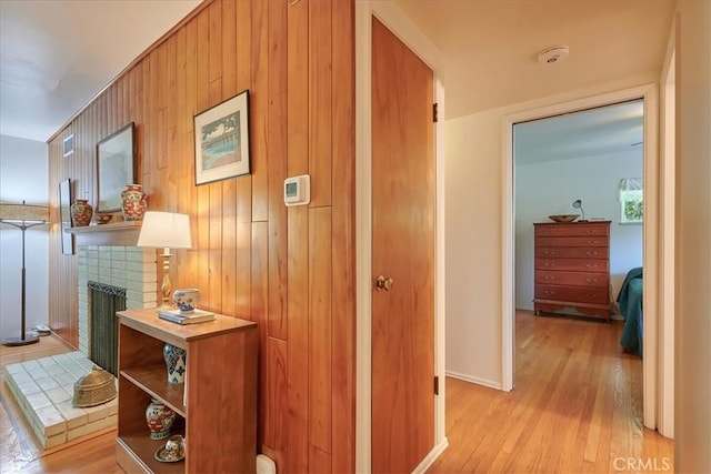 corridor with wood walls and light wood-style flooring