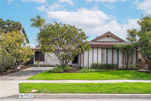 view of front of property with aphalt driveway, a front lawn, and stucco siding