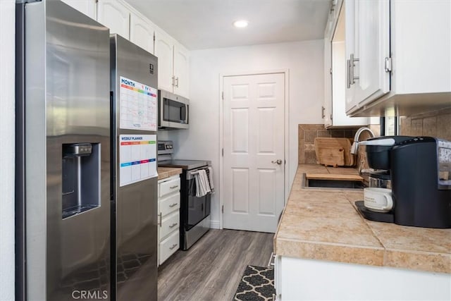 kitchen with tasteful backsplash, appliances with stainless steel finishes, dark wood-type flooring, white cabinetry, and a sink