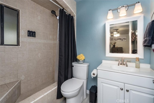 full bathroom featuring toilet, a ceiling fan, tiled shower, and vanity