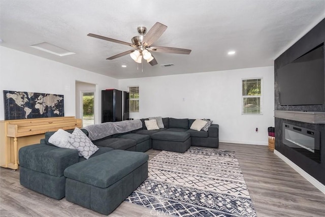 living area with visible vents, plenty of natural light, baseboards, and wood finished floors