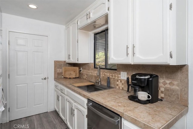 kitchen with stainless steel dishwasher, dark wood-type flooring, a sink, and white cabinets