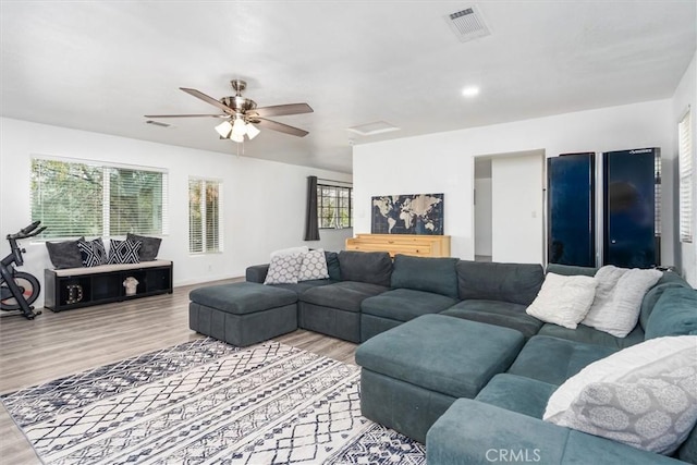 living room featuring a ceiling fan, visible vents, and wood finished floors