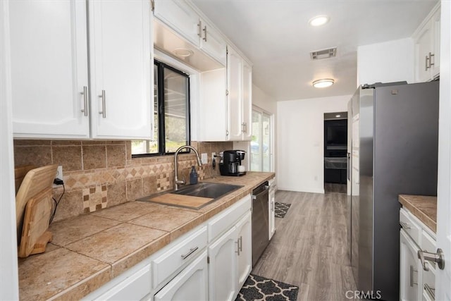 kitchen with stainless steel appliances, white cabinets, visible vents, and a sink