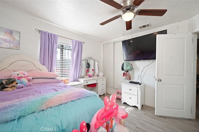 bedroom featuring ceiling fan, wood finish floors, a closet, and visible vents