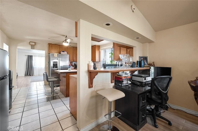 27447 Cypress St, Highland, CA 92346 - kitchen featuring brown cabinetry, ceiling fan, a breakfast bar area, an office area, and a peninsula