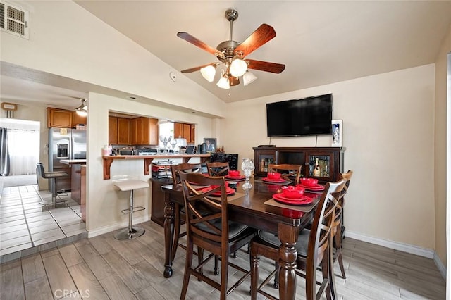 dining room with lofted ceiling, light wood finished floors, visible vents, and a ceiling fan