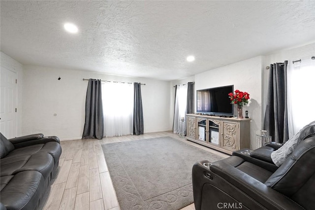 living area featuring light wood-style floors, a textured ceiling, and baseboards