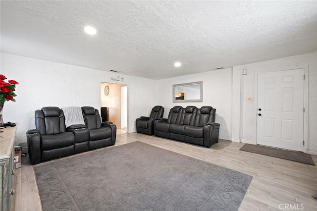 living room with light wood-type flooring, a textured ceiling, and baseboards