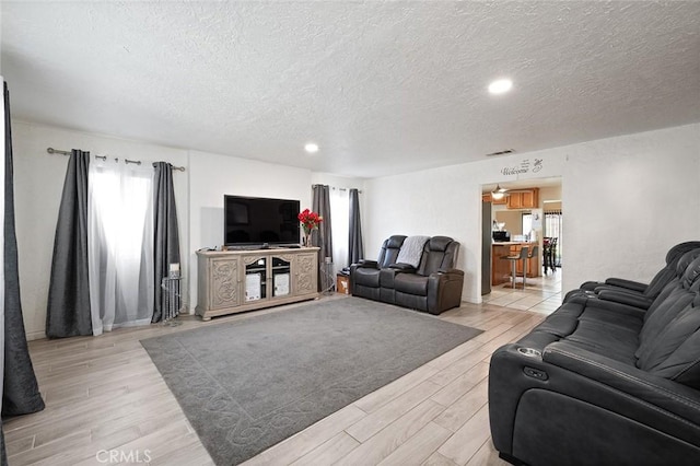 living area featuring a textured ceiling, visible vents, and light wood-style floors