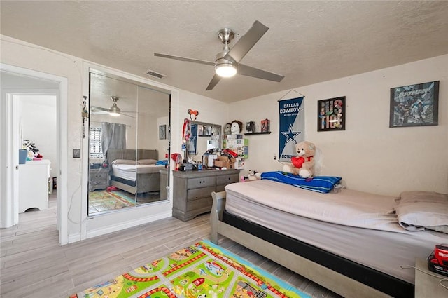 bedroom with visible vents, ceiling fan, a textured ceiling, light wood-type flooring, and a closet