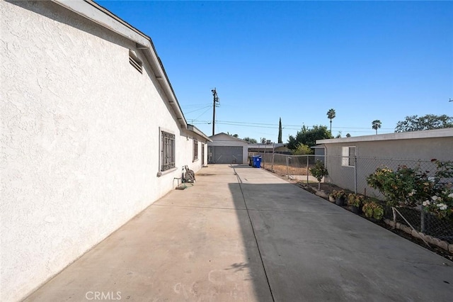 view of property exterior with fence, a detached garage, an outdoor structure, and stucco siding