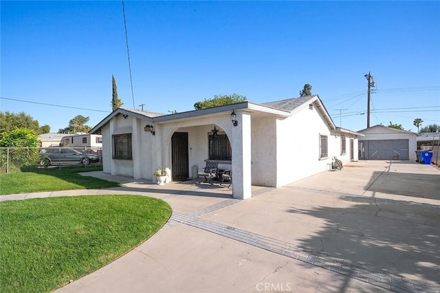 view of front of house featuring a front yard, fence, an outdoor structure, and stucco siding