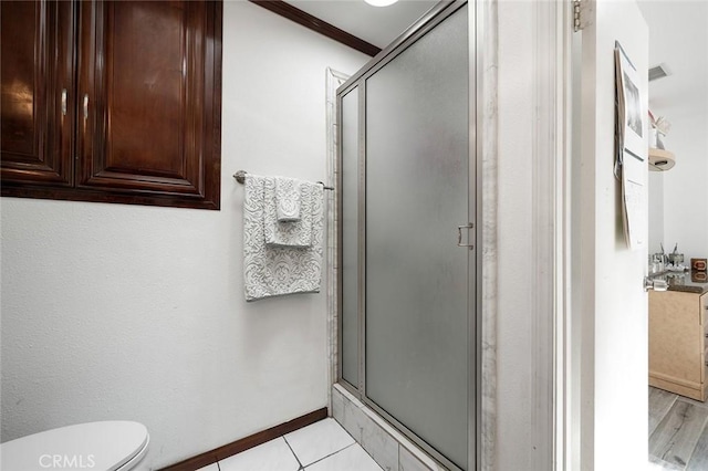 bathroom featuring a stall shower, tile patterned floors, toilet, and baseboards