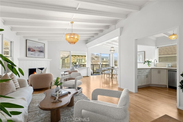 living area featuring light wood-style floors, a brick fireplace, lofted ceiling with beams, and baseboards