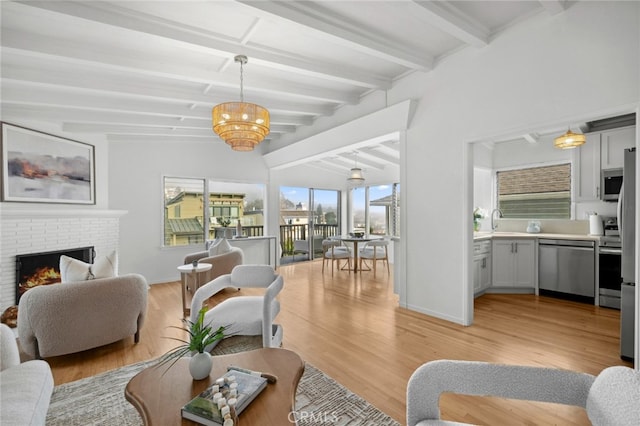 living area featuring beamed ceiling, a fireplace, light wood-style flooring, and baseboards