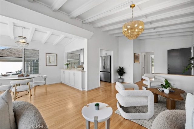 living room with vaulted ceiling with beams, light wood-style flooring, baseboards, and an inviting chandelier