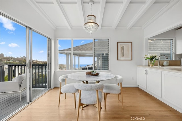 sunroom / solarium with an inviting chandelier, a sink, and beamed ceiling