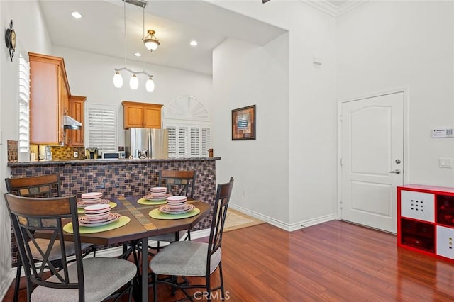 dining space with baseboards, wood finished floors, and recessed lighting