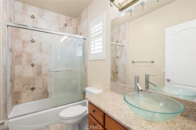 bathroom featuring bath / shower combo with glass door, tile patterned flooring, vanity, and toilet