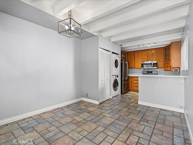 kitchen featuring stacked washer / dryer, baseboards, light countertops, appliances with stainless steel finishes, and brown cabinetry