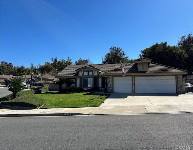 view of front of house with a garage, stone siding, concrete driveway, a tiled roof, and a front yard