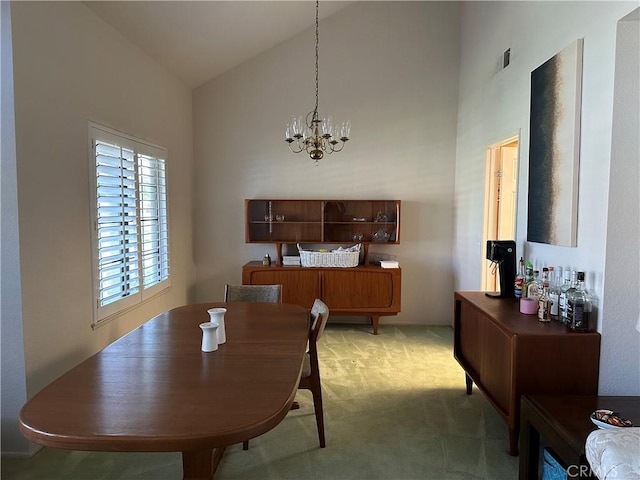 dining room featuring light carpet, high vaulted ceiling, and an inviting chandelier