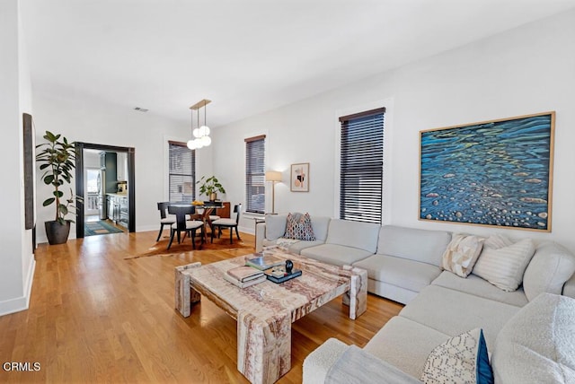 living area with visible vents, baseboards, and wood finished floors