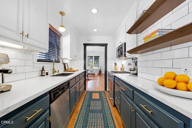 kitchen with light wood-style floors, appliances with stainless steel finishes, white cabinets, and a sink