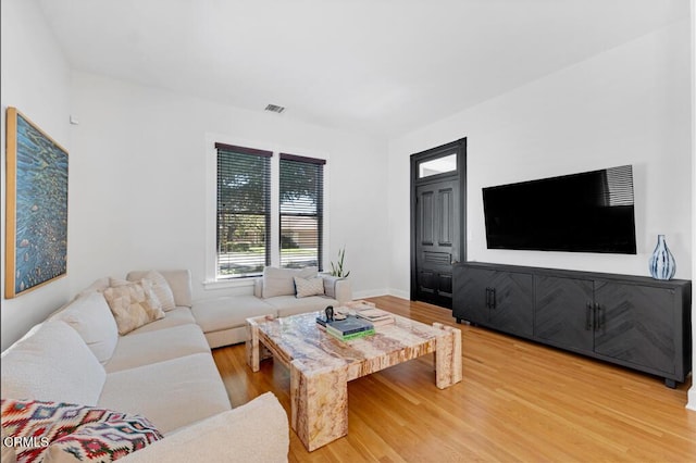 living area with wood finished floors, visible vents, and baseboards