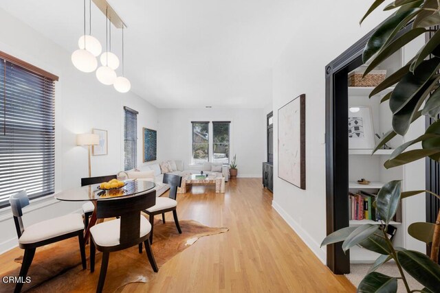 dining space featuring light wood-type flooring and baseboards