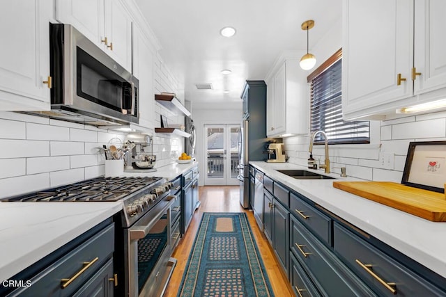 kitchen featuring blue cabinetry, appliances with stainless steel finishes, a sink, and white cabinetry