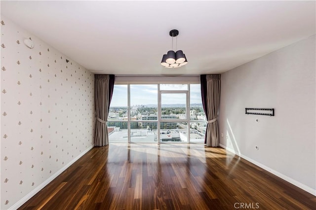 spare room featuring wood finished floors, baseboards, and wallpapered walls