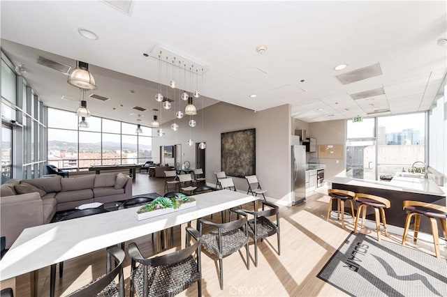 dining area with light wood-type flooring, plenty of natural light, and visible vents