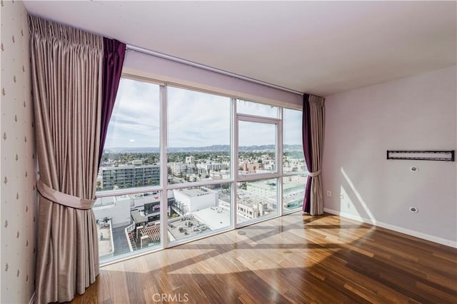 spare room featuring baseboards, a city view, and wood finished floors