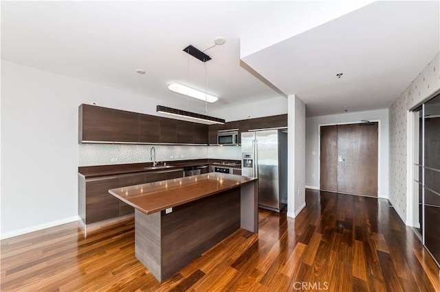 kitchen featuring dark brown cabinetry, dark wood-style floors, modern cabinets, appliances with stainless steel finishes, and a sink