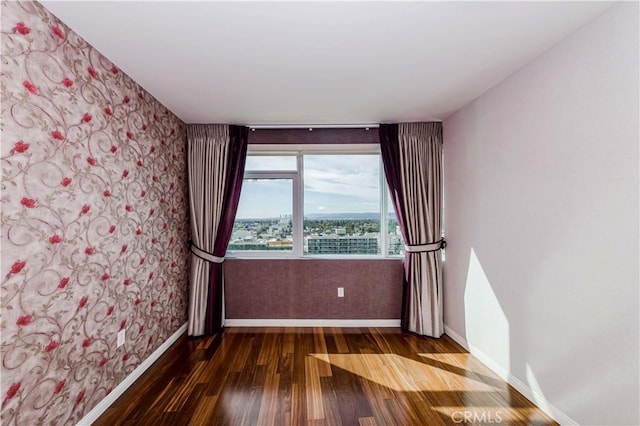 empty room featuring dark wood-style floors and baseboards