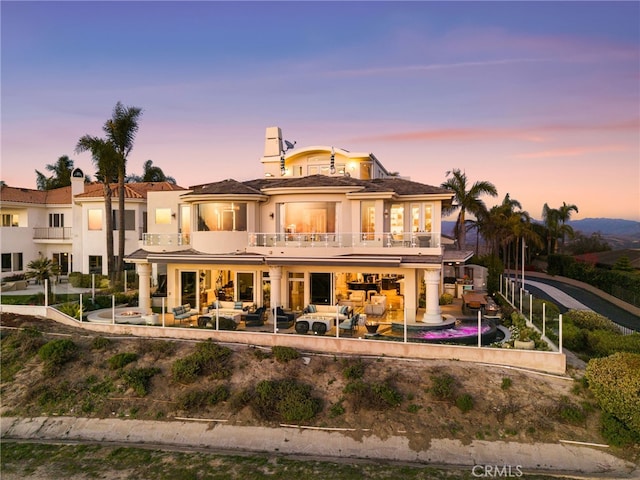 back of property with a balcony, a patio area, and stucco siding