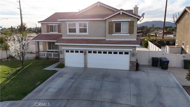 traditional-style home featuring an attached garage, fence, a tiled roof, stucco siding, and a front yard