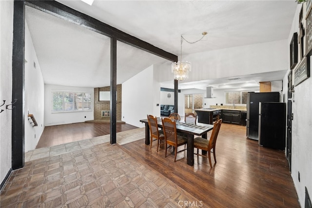 dining room with lofted ceiling with beams, an inviting chandelier, and wood finished floors