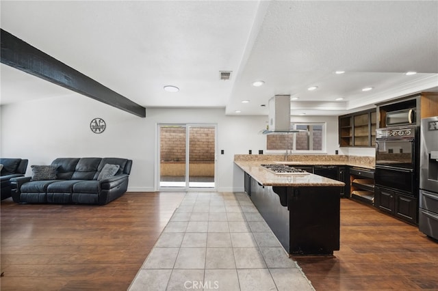 kitchen with visible vents, island range hood, wood finished floors, a peninsula, and black appliances