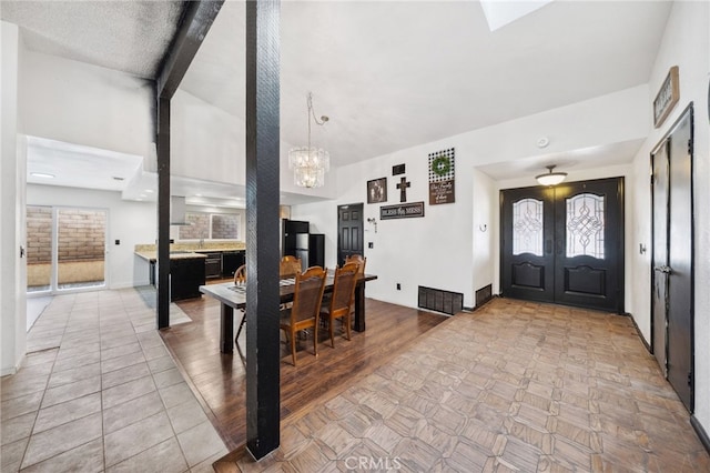 tiled entrance foyer with an inviting chandelier, baseboards, and visible vents