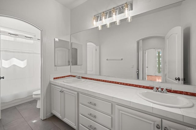 full bath featuring tile patterned flooring, a sink, toilet, and double vanity