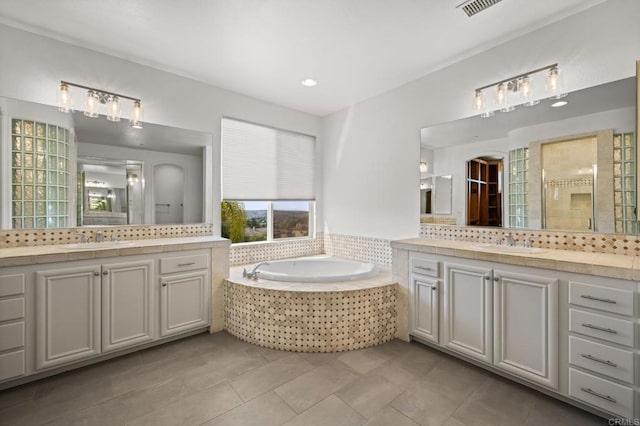 bathroom featuring a garden tub, a shower stall, two vanities, and a sink