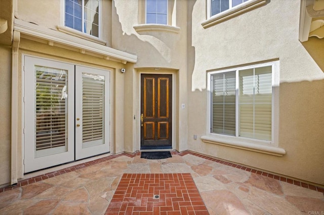 view of exterior entry with french doors and stucco siding