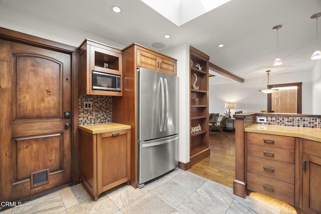 kitchen with hanging light fixtures, light countertops, stainless steel appliances, open shelves, and backsplash